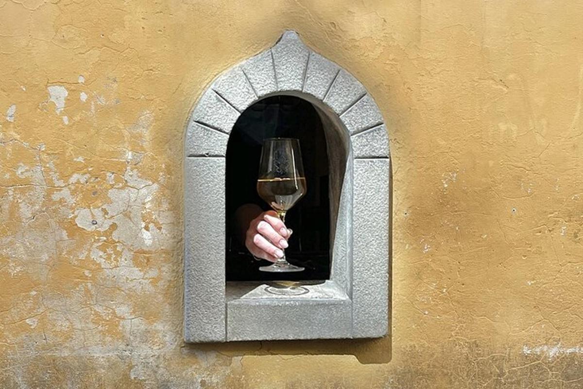 Una mano sosteniendo una copa de vino en una pared