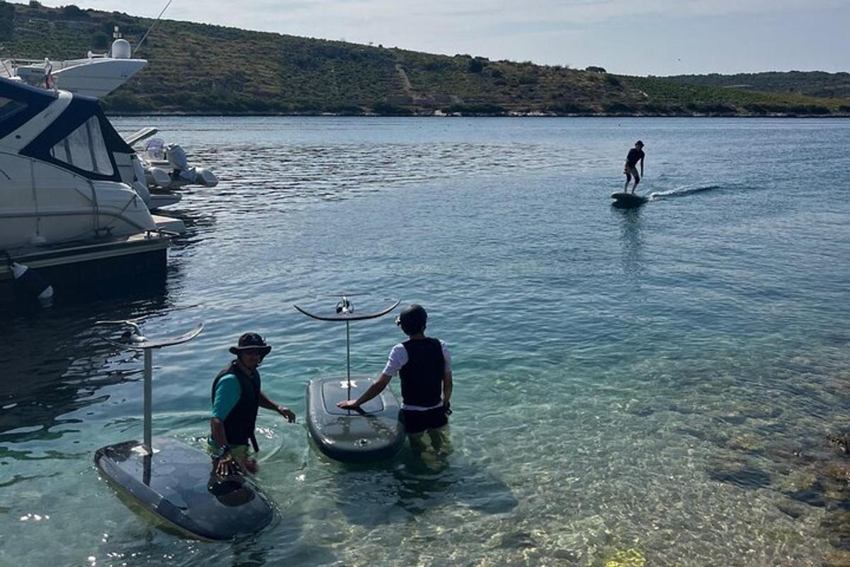tři lidé stojí ve vodě na paddleboardech