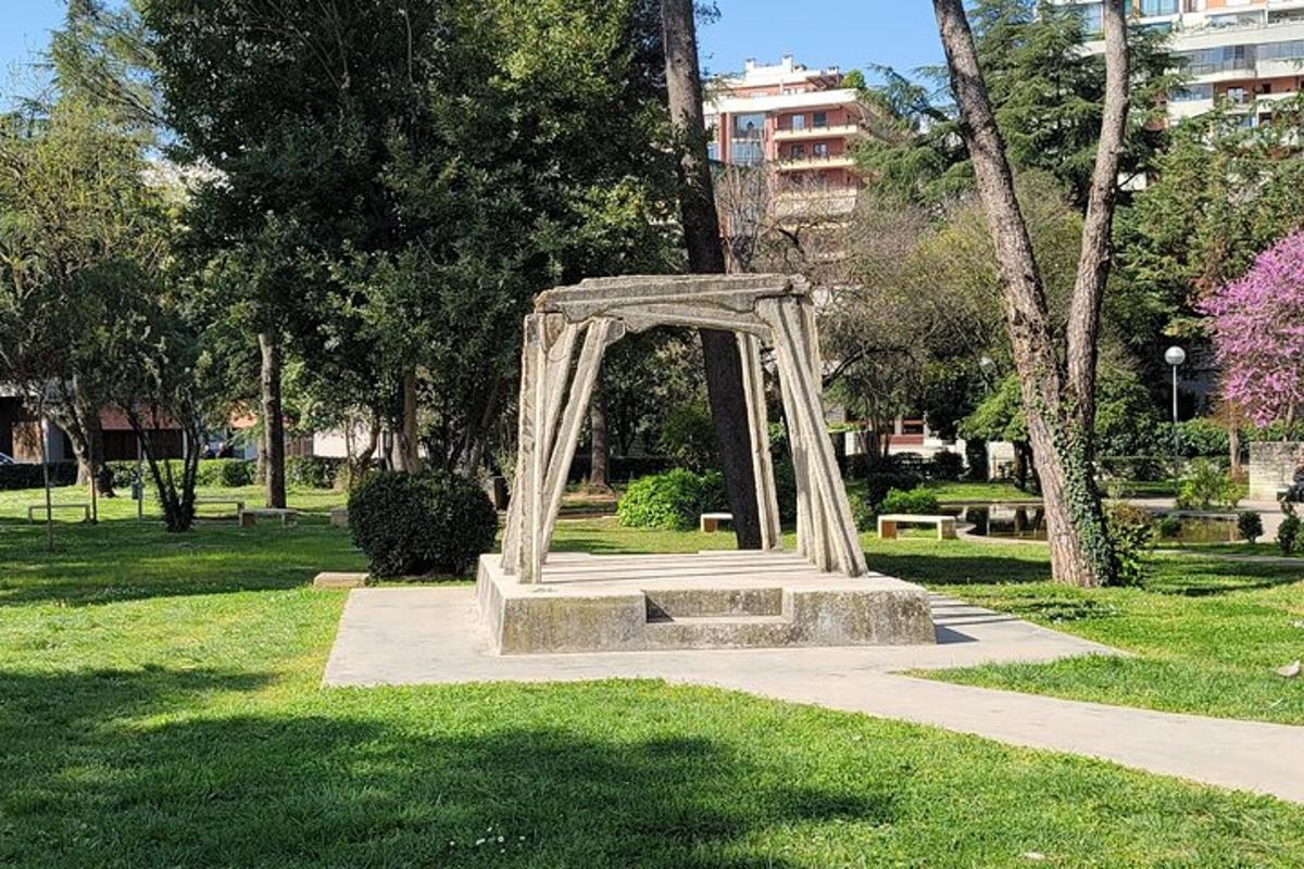 un arc metàl·lic en un parc amb gespa i arbres