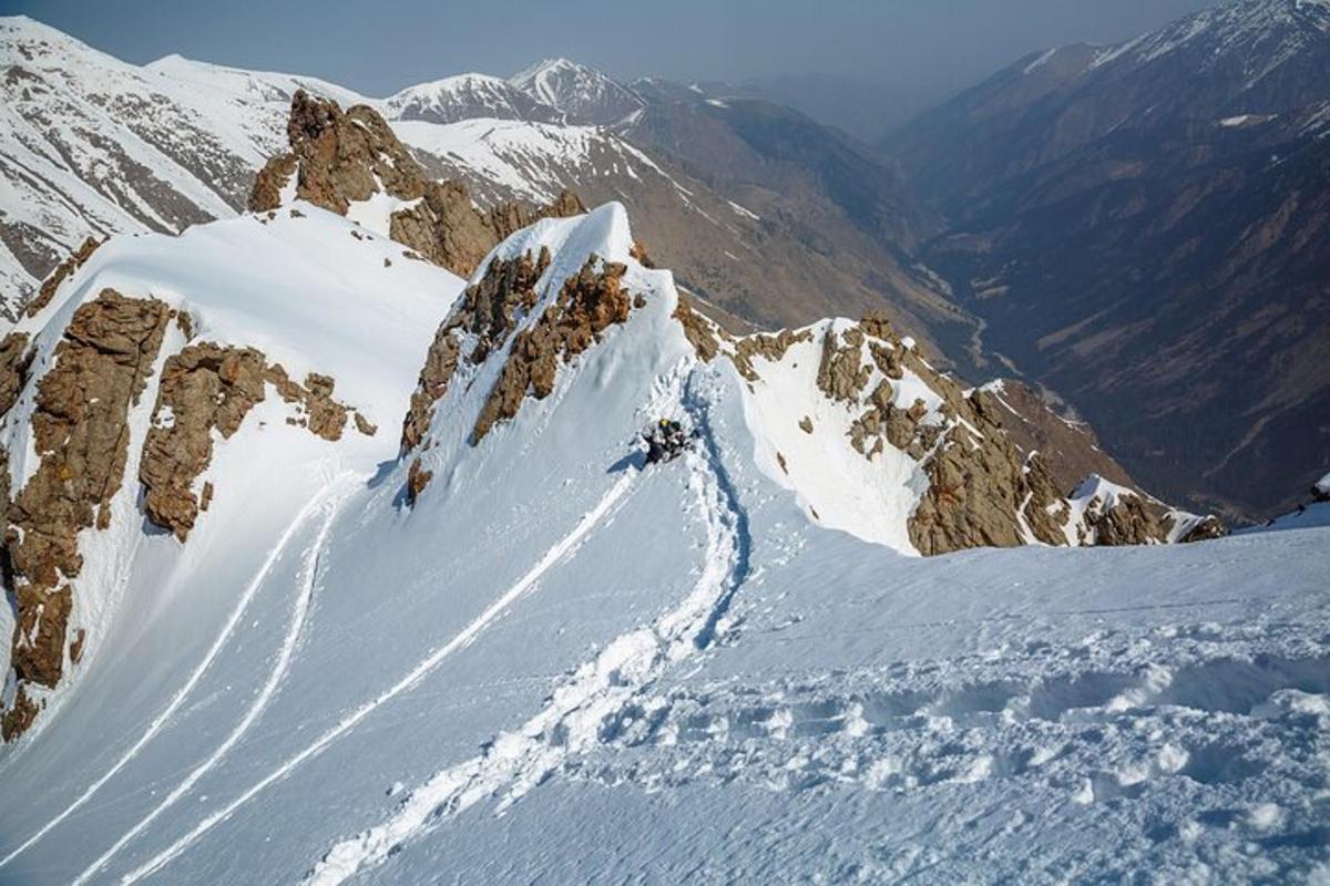 ang isang tao ay nag-i-ski pababa sa isang bundok na natatakpan ng niyebe