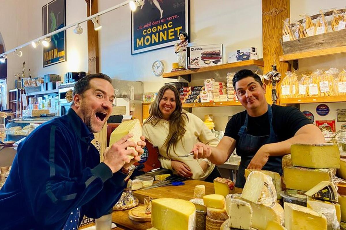 a group of three people standing in a cheese shop