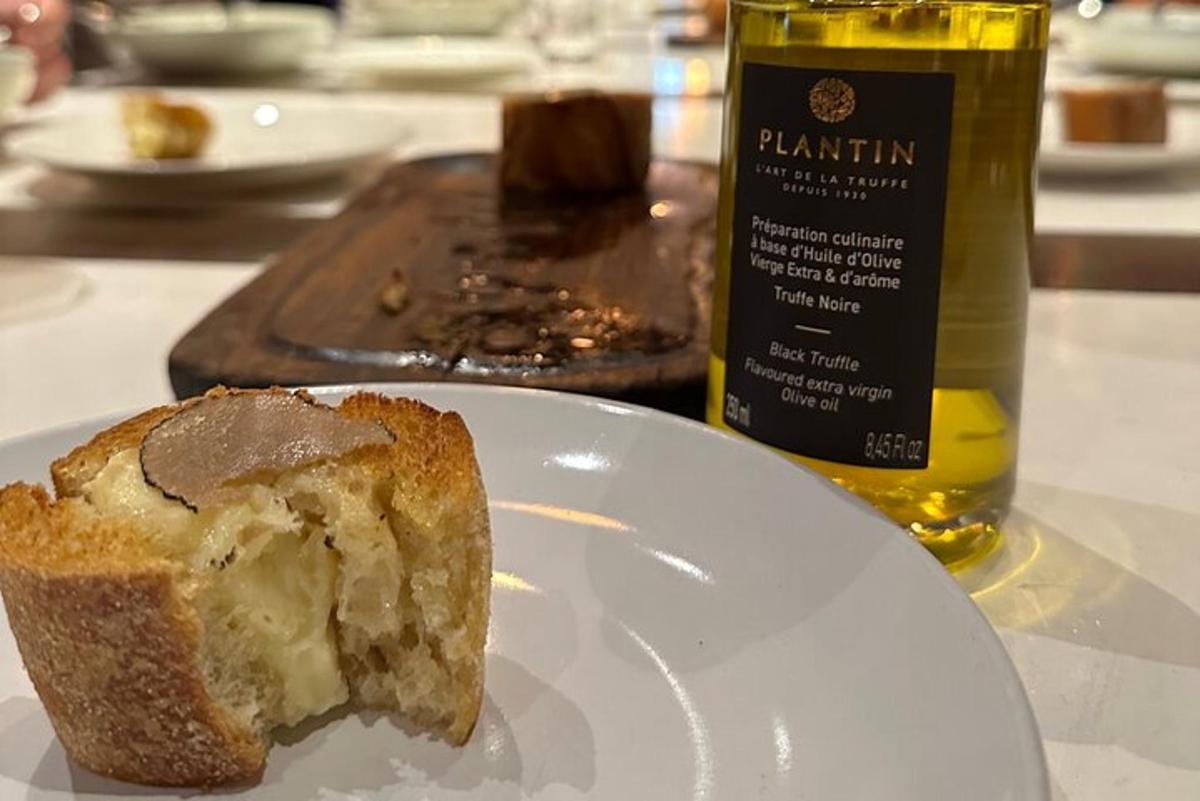 a piece of bread on a white plate next to a bottle of oil