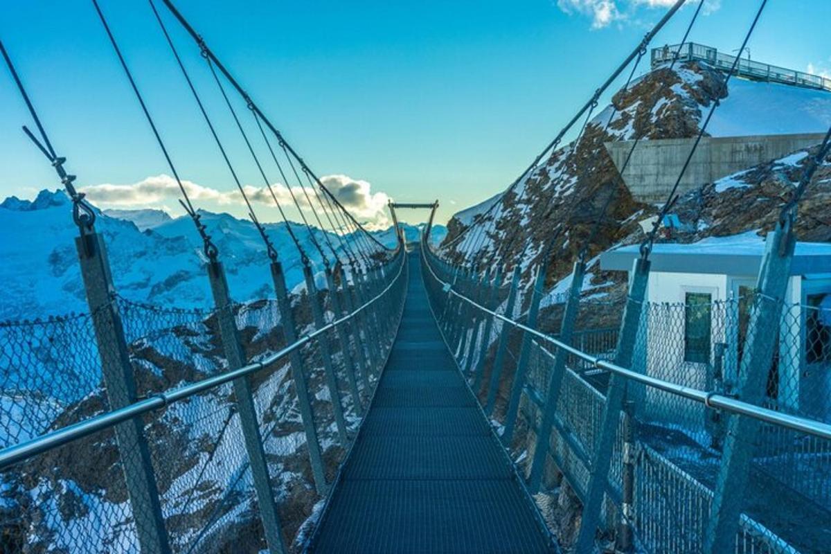 uma ponte suspensa sobre uma montanha com neve
