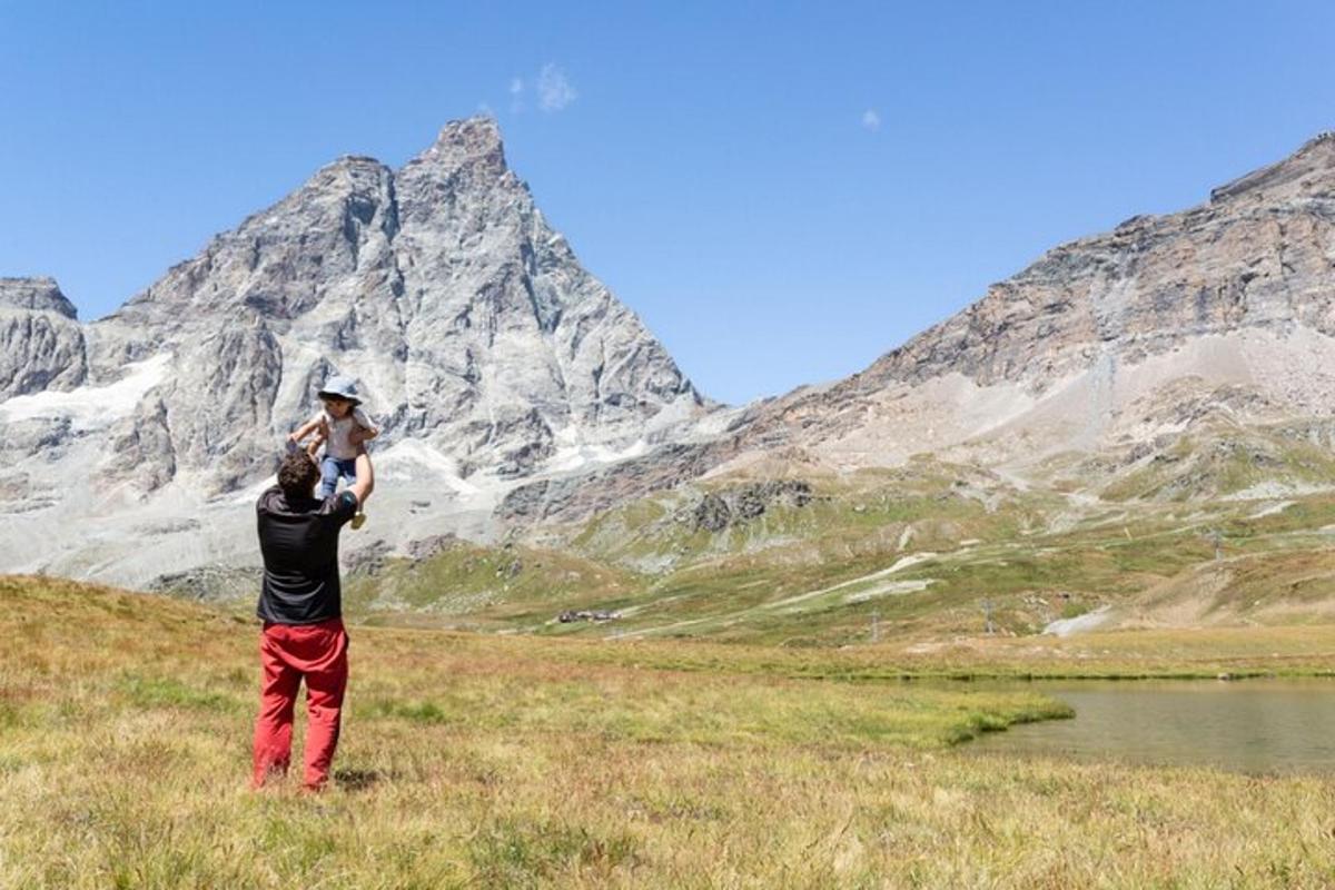 a man holding a child in front of a mountain