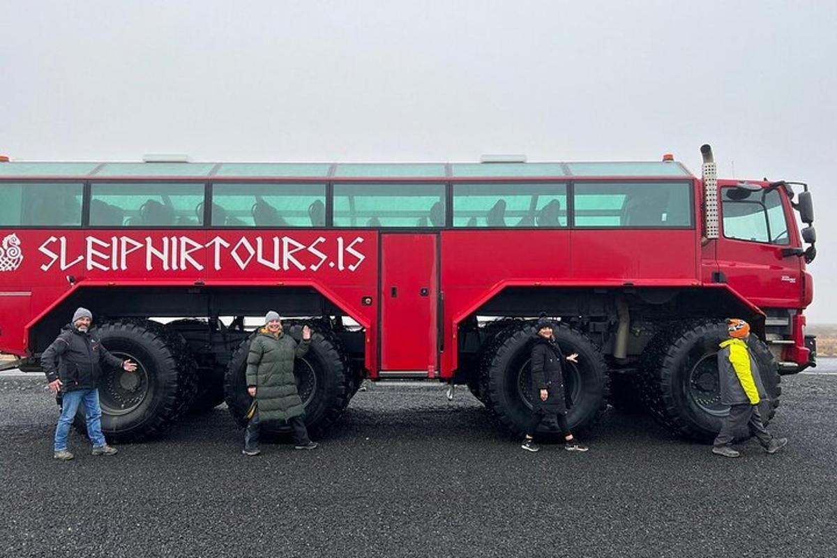 un gruppo di persone in piedi accanto a un grande autobus rosso