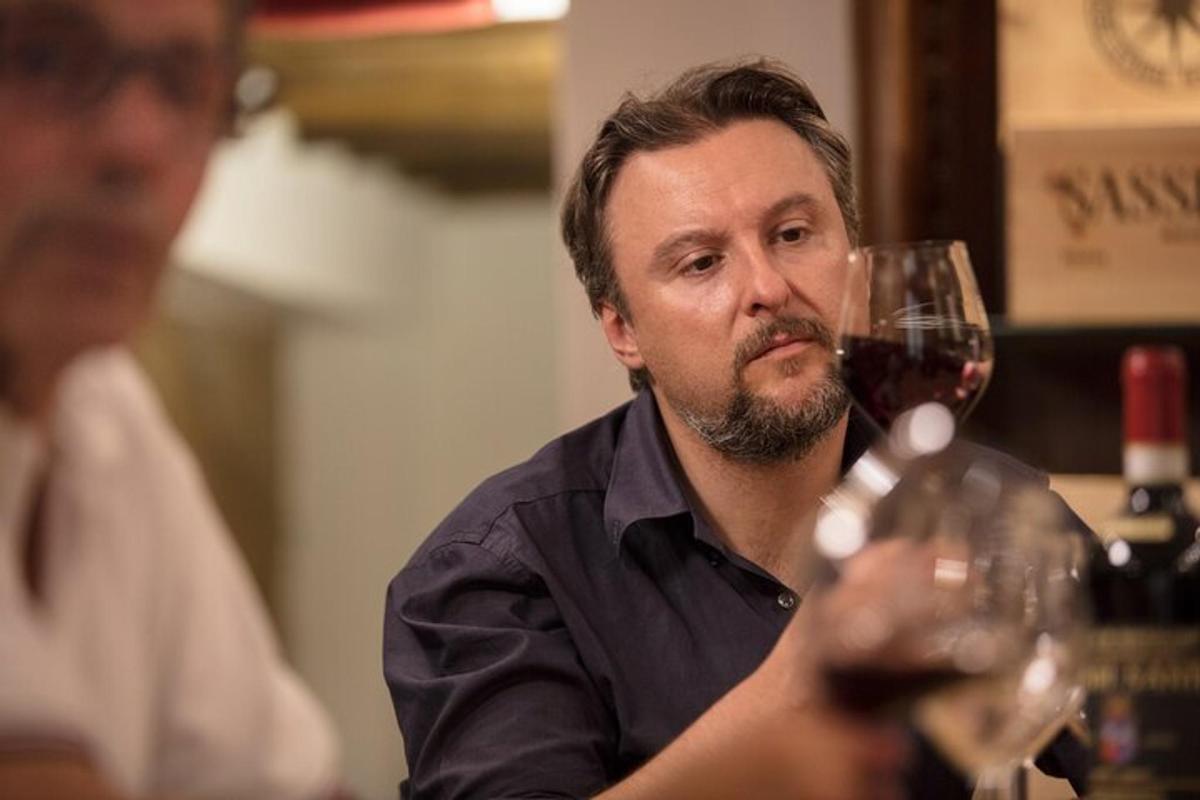 un uomo che tiene in mano un bicchiere di vino rosso