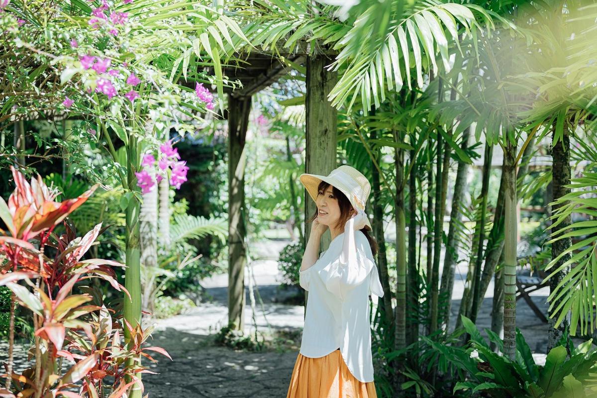 a woman wearing a hat standing in a garden