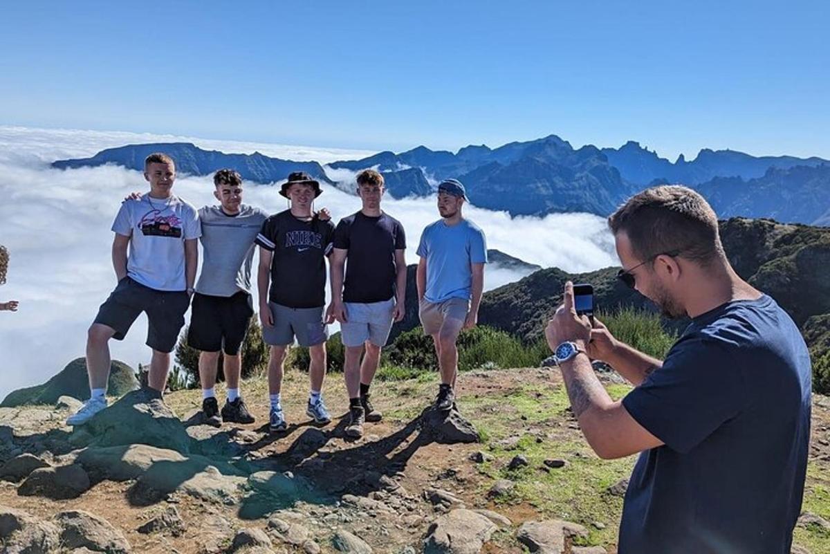 moški fotografira skupino moških, ki stojijo na gori