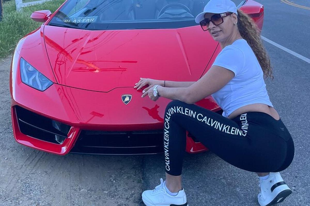 žena sedící na kapotě červeného auta