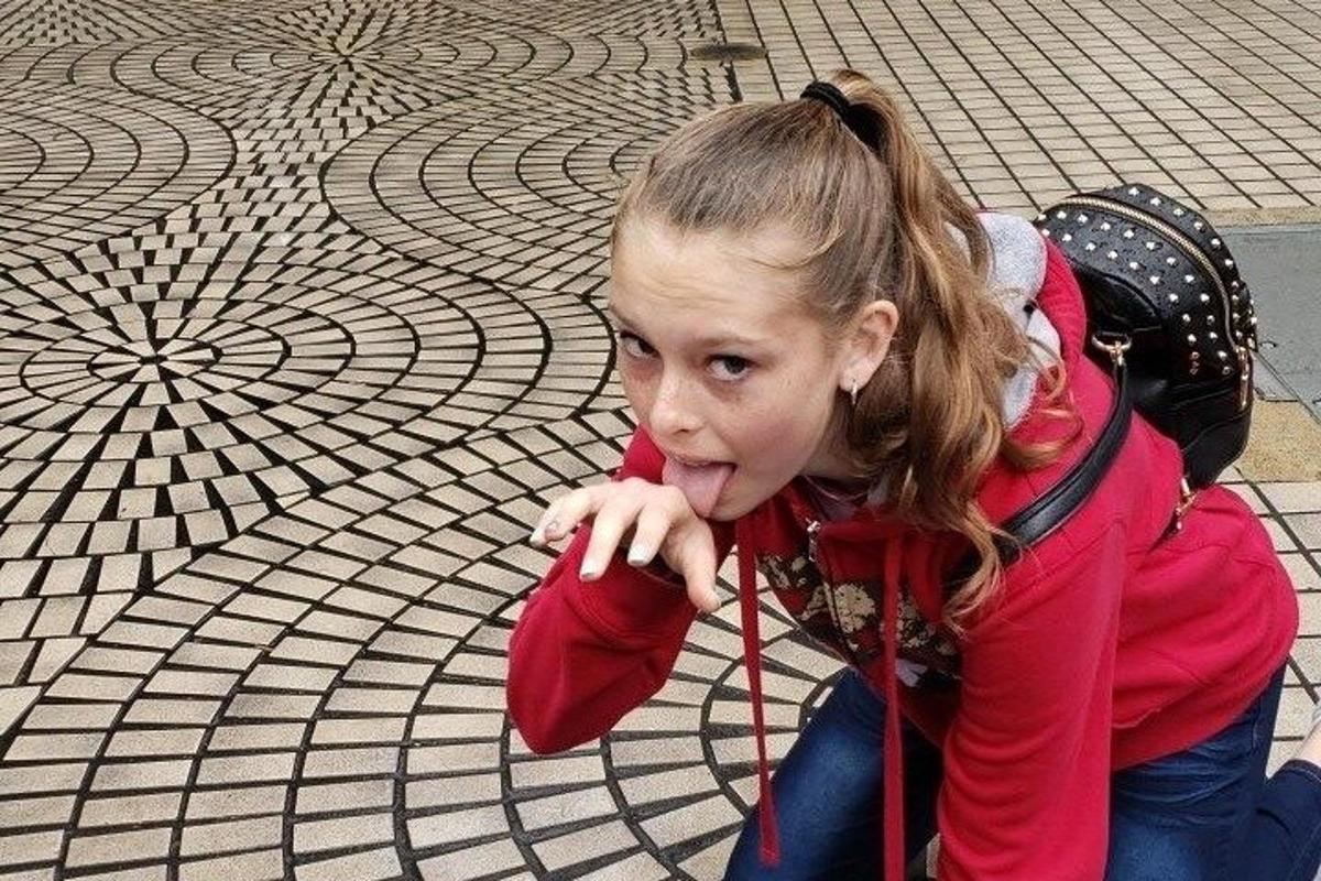 Una niña sentada en el suelo mirando el suelo.