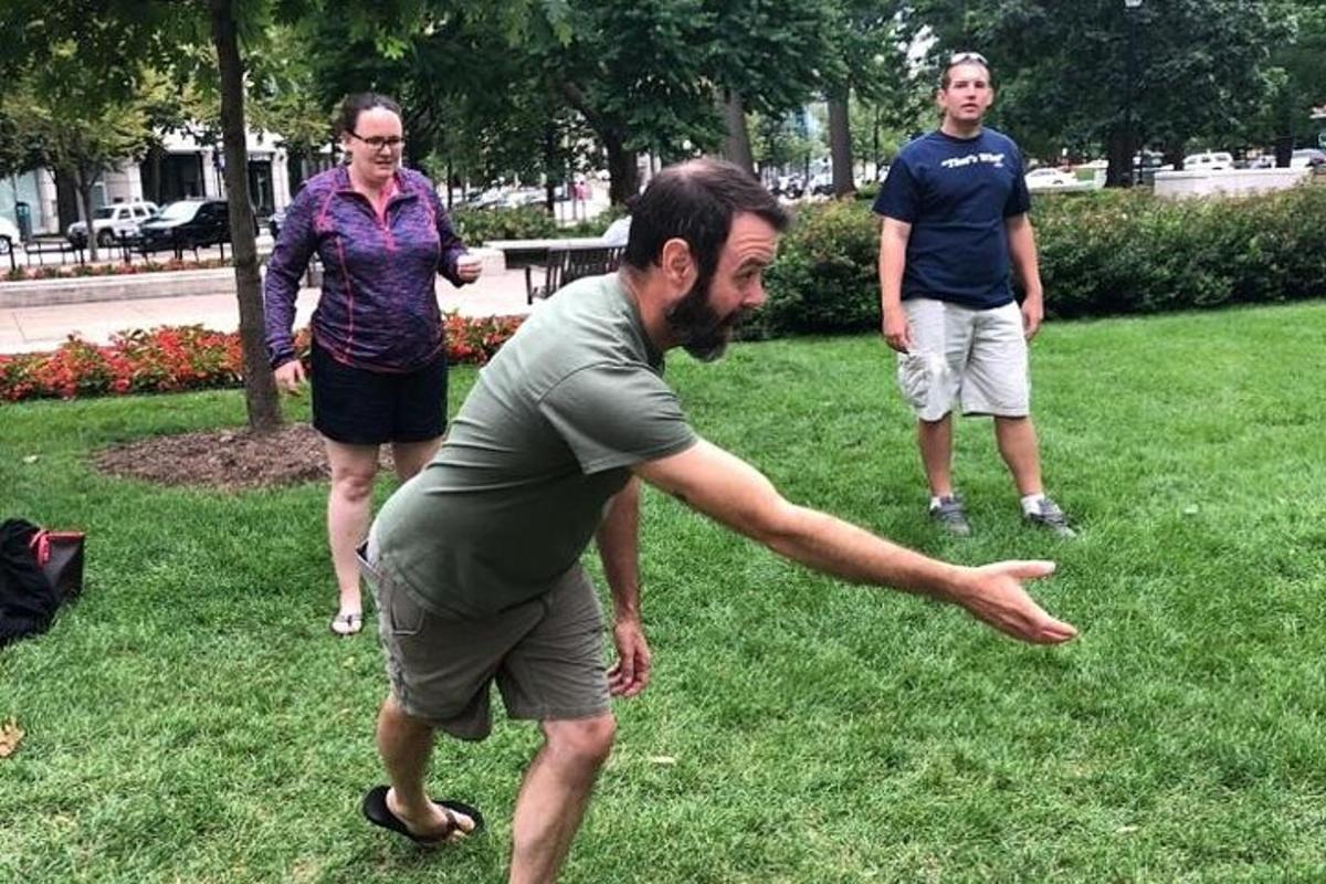 a man throwing a frisbee in a park with two women