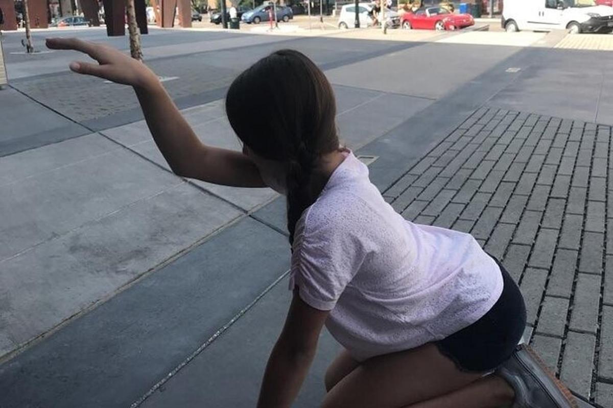 Una mujer está sentada en el suelo en la calle.