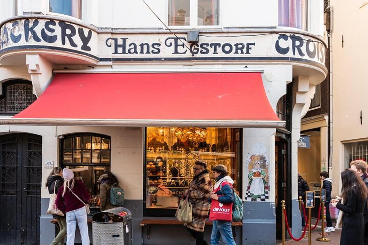 des gens debout à l'extérieur d'un magasin avec un auvent rouge