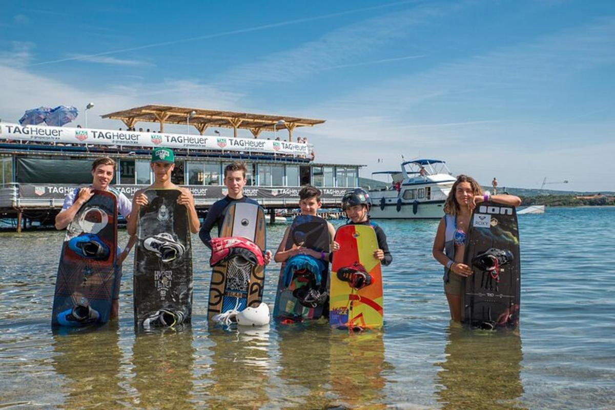 a group of people standing in the water with their snowboards