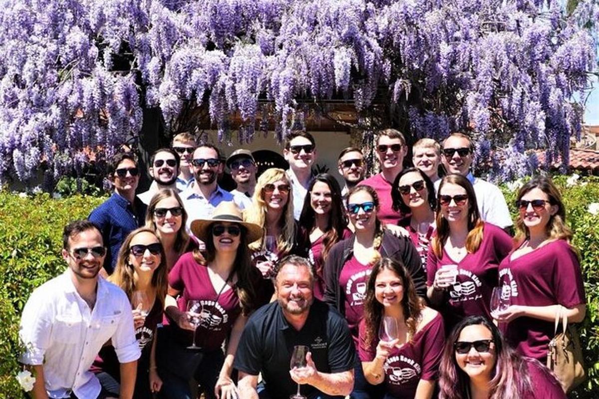 un gruppo di persone in posa per una foto davanti a fiori viola