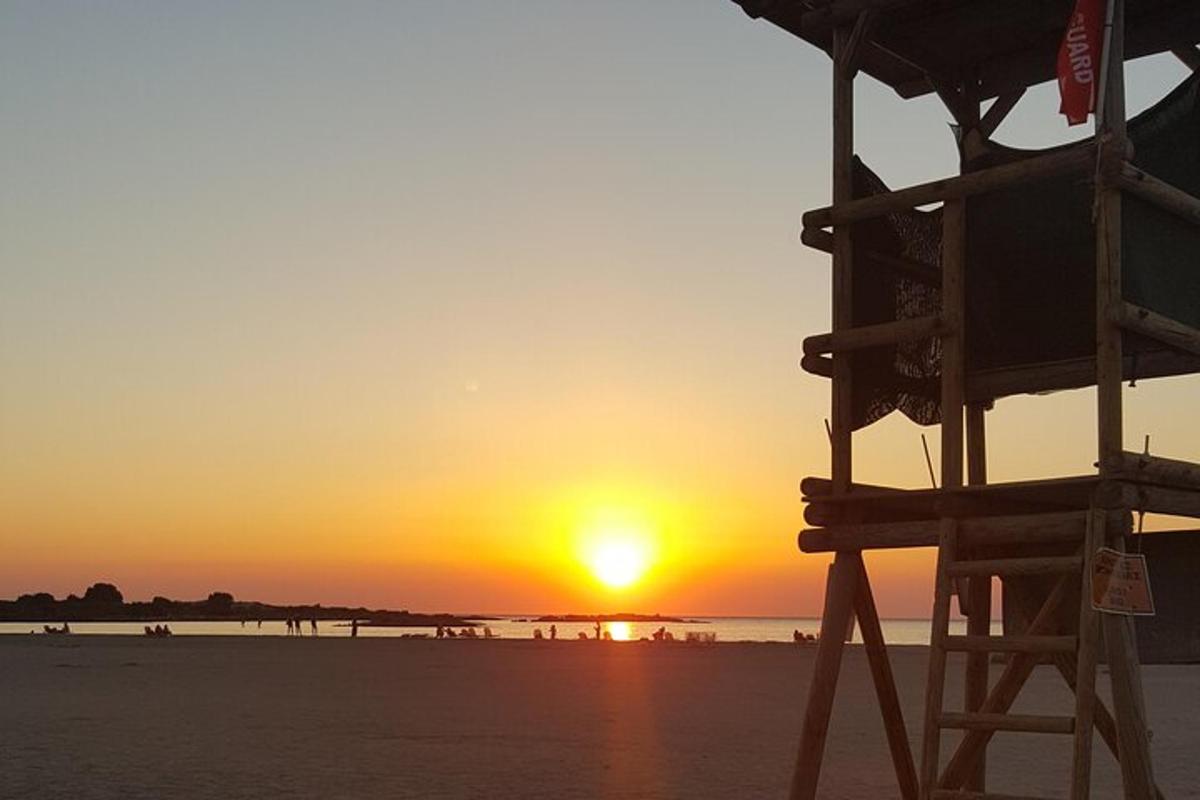 a sunset on the beach with a lifeguard chair