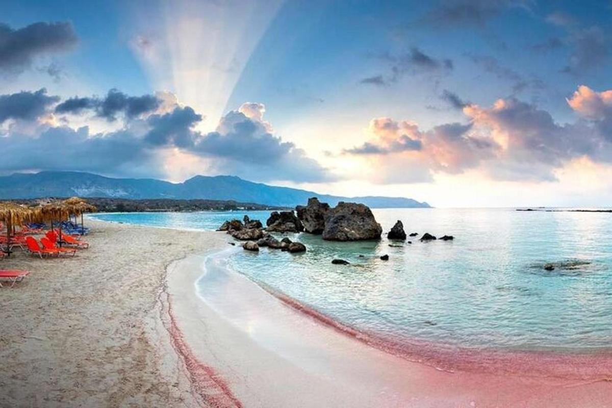 một bãi biển có đá trong nước với bầu trời nhiều mây