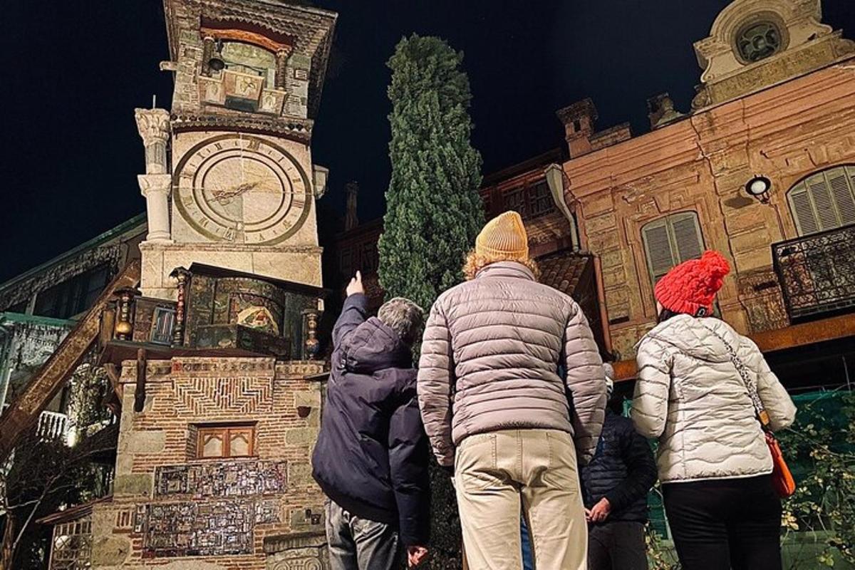 un grup de oameni care stau în fața unui turn cu ceas