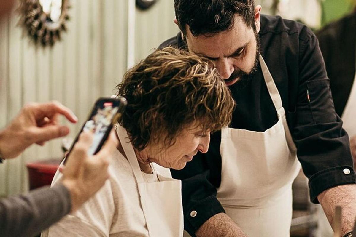 a man and a woman in a kitchen taking a picture with a cell phone