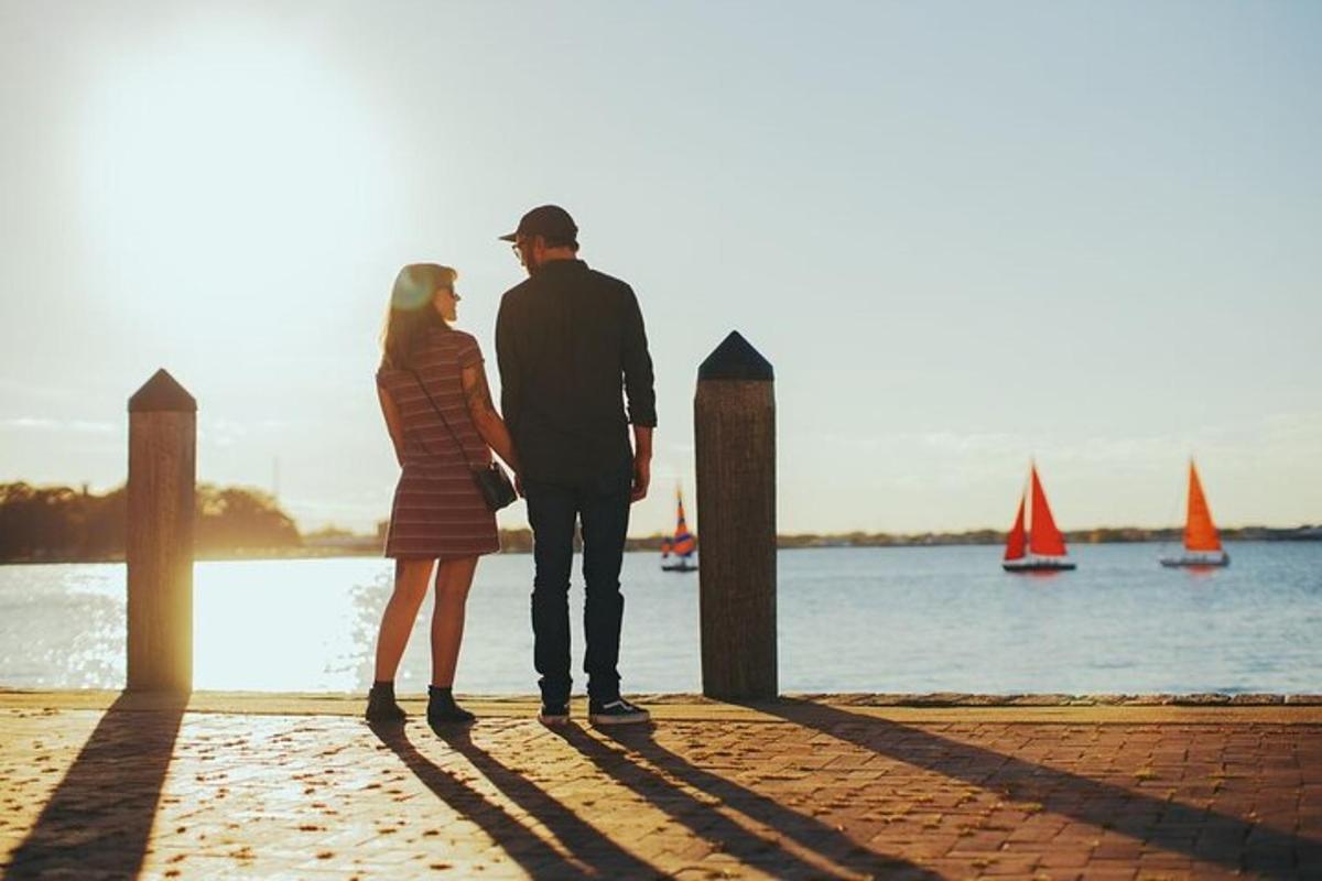 a man and a woman standing on the beach looking at the water