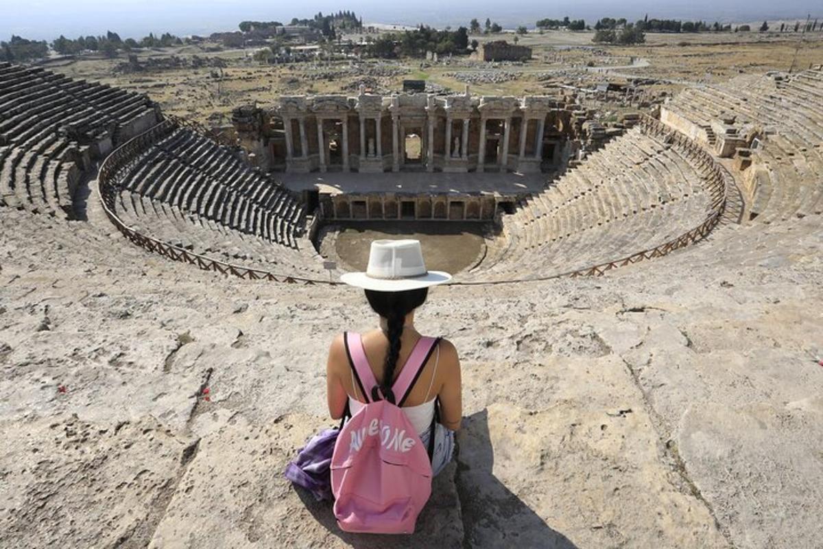eine Frau mit Hut, die in einem Amphitheater sitzt