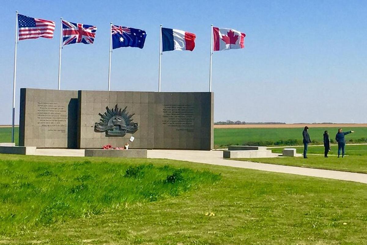 eine Gruppe von Menschen steht mit Flaggen vor einem Denkmal