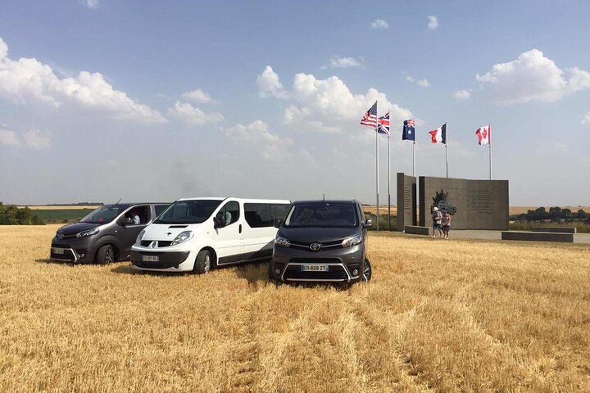 three cars parked in a field of dry grass