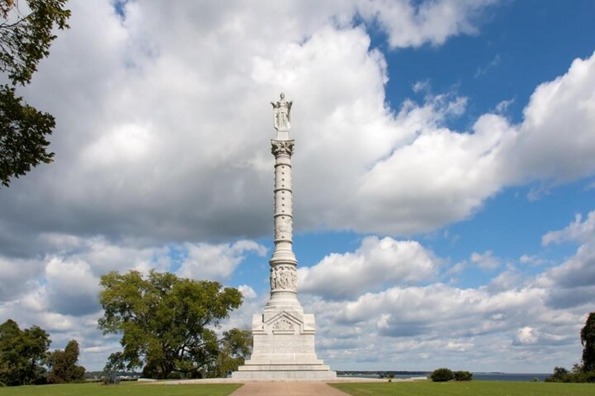 a statue in a field with a cloudy sky