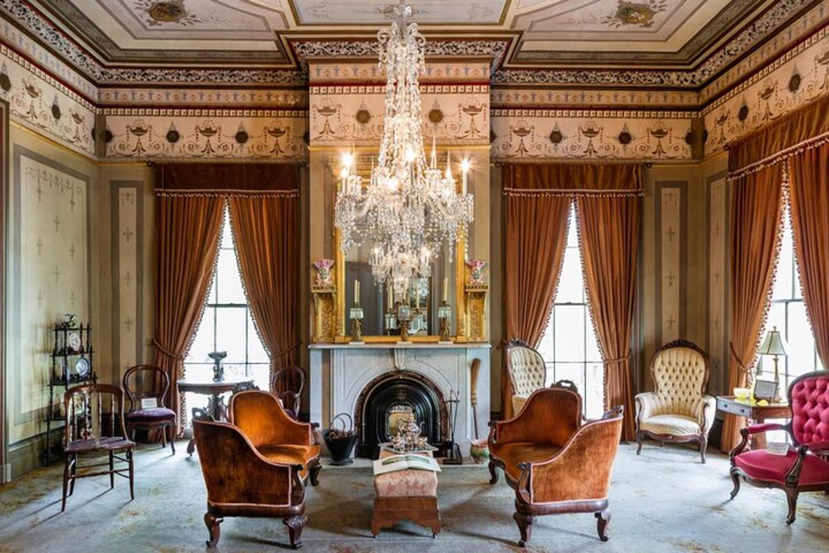 a living room with a fireplace and chairs and a chandelier