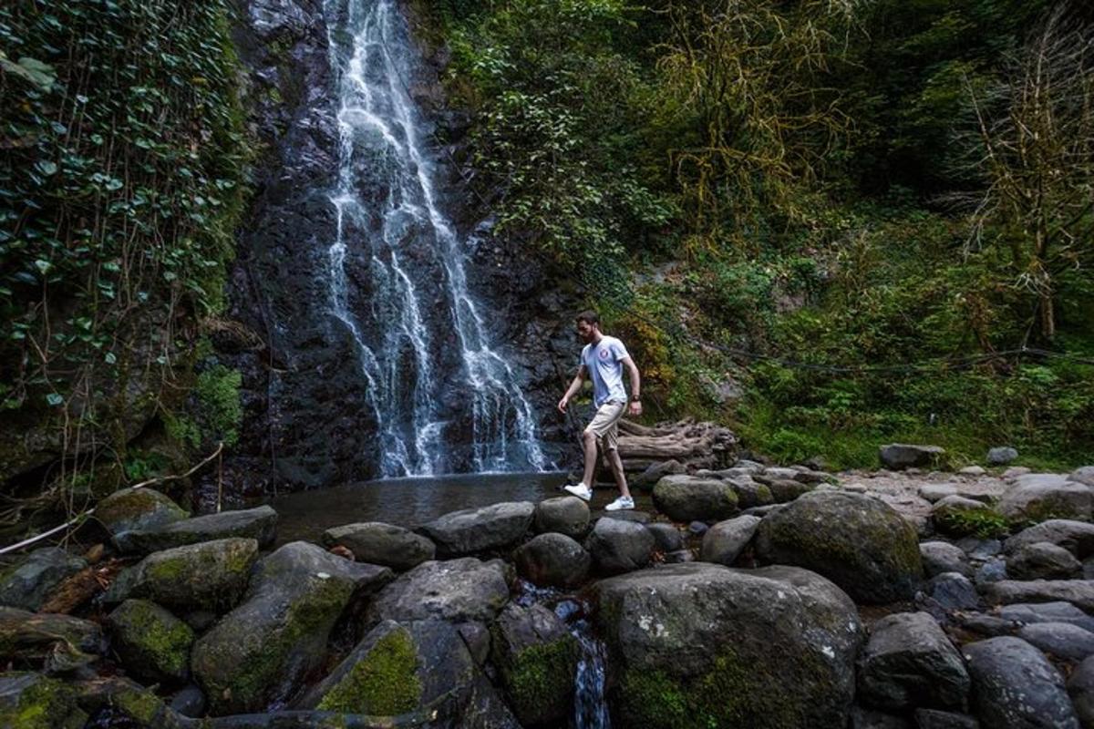 a man standing on rocks in front of a waterfall