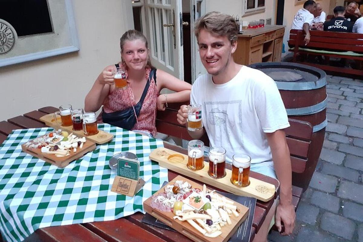 moški in ženska sedita za mizo s pivom