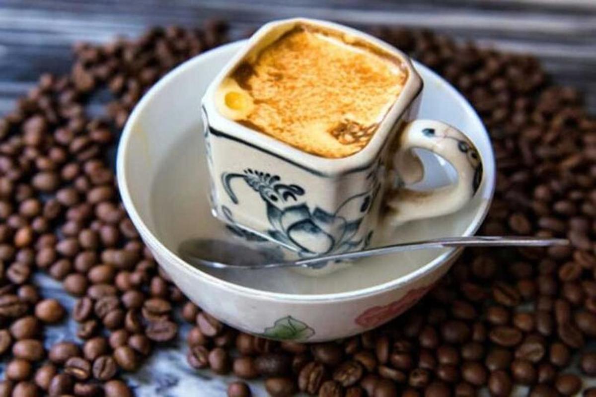 una tazza di caffè su un piatto con chicchi di caffè