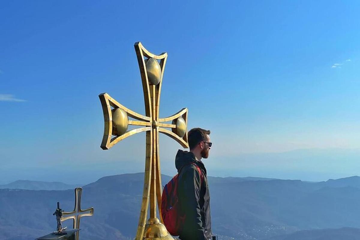 a man standing next to a golden cross