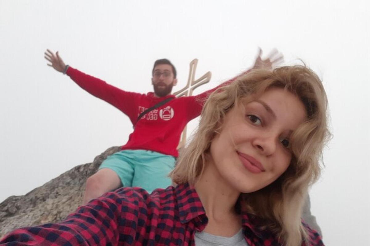 a man and a woman sitting on top of a rock
