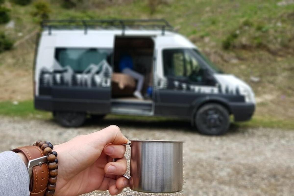 a person holding a cup in front of a van