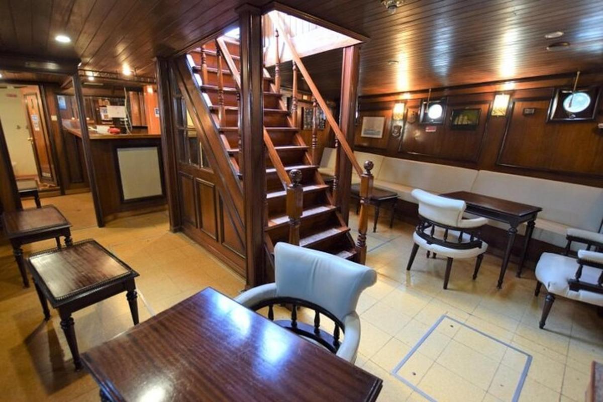 Un restaurante con escalera y mesas y sillas.