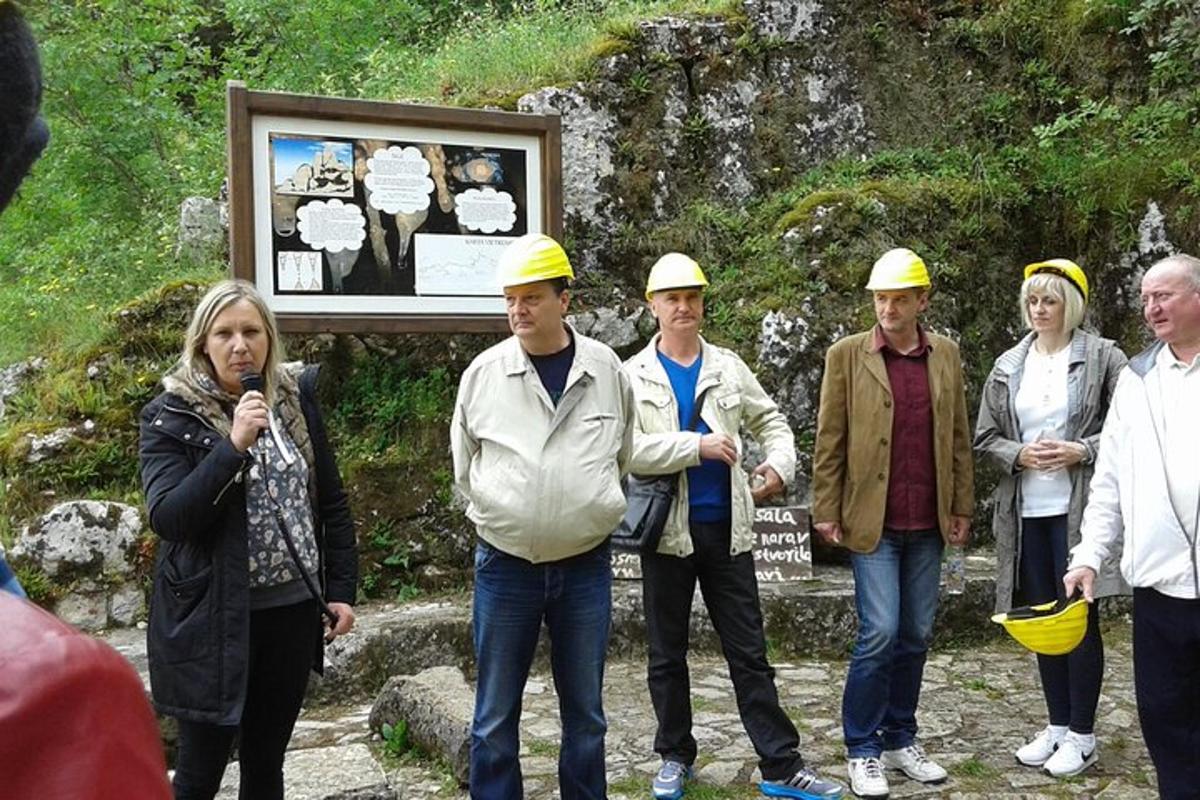 grupp inimesi, kes kannavad kaitsekiivreid ja seisavad sildi ees