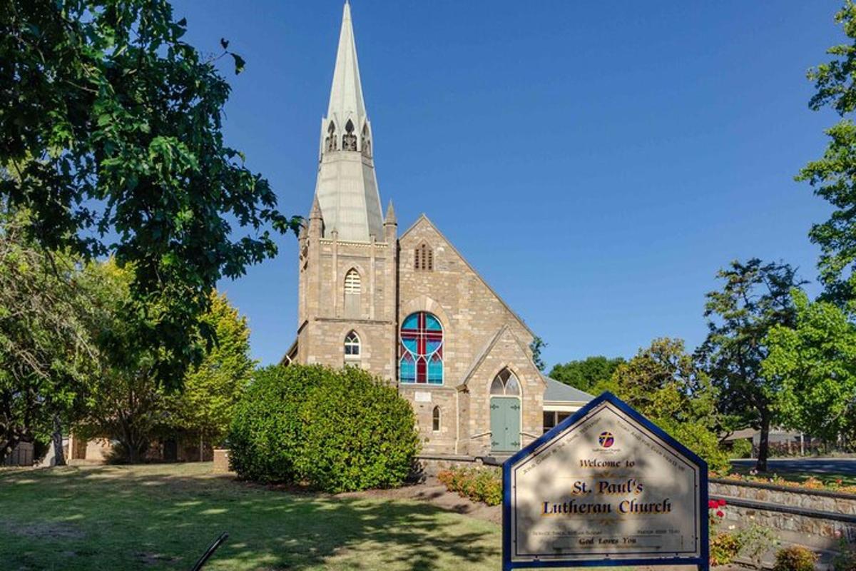 Una iglesia con una torre y un cartel delante de ella.