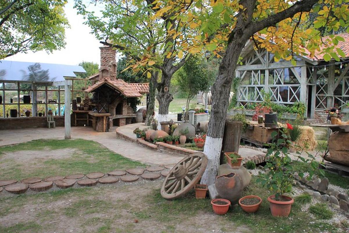 Un jardín con una rueda de madera y un edificio.