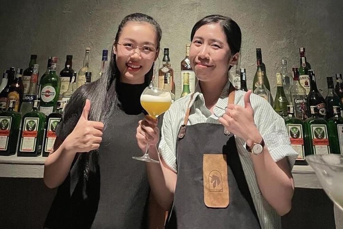 hai người phụ nữ đứng trong quán bar với một ly rượu vang