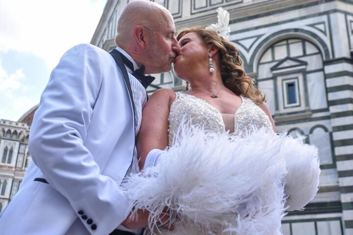 una sposa e uno sposo che si baciano davanti a un edificio