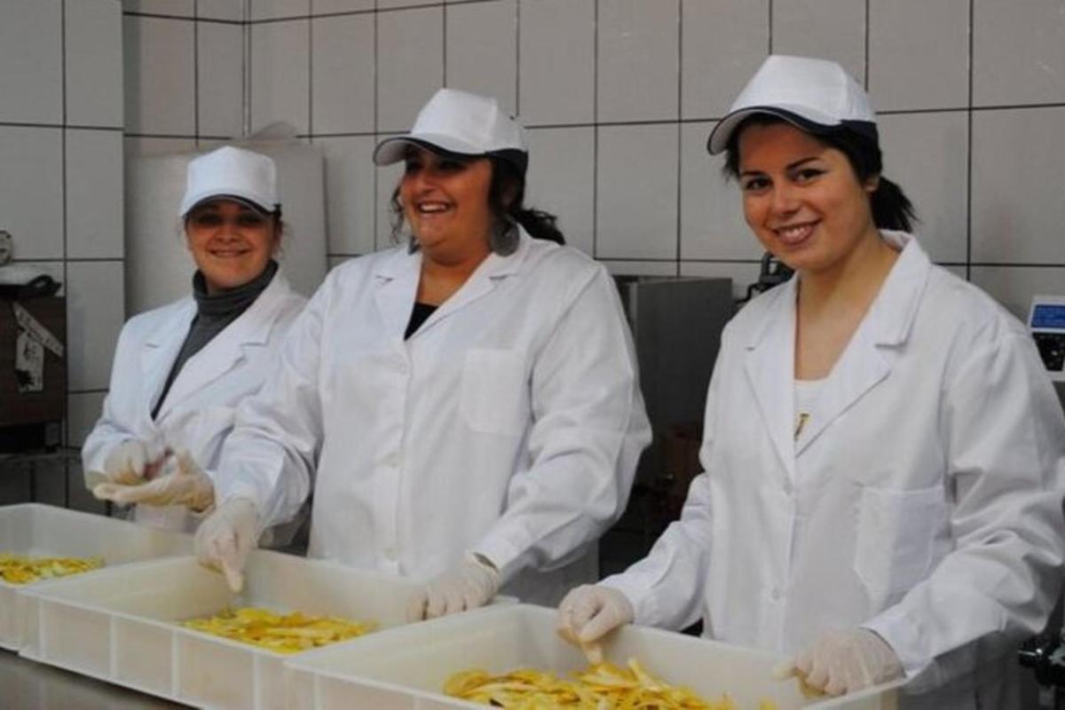 Un grupo de tres mujeres en una cocina preparando comida.