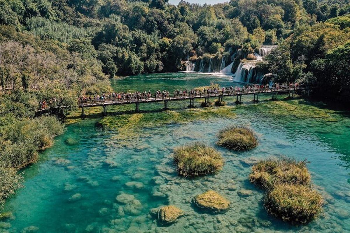a group of people walking across a bridge over a waterfall