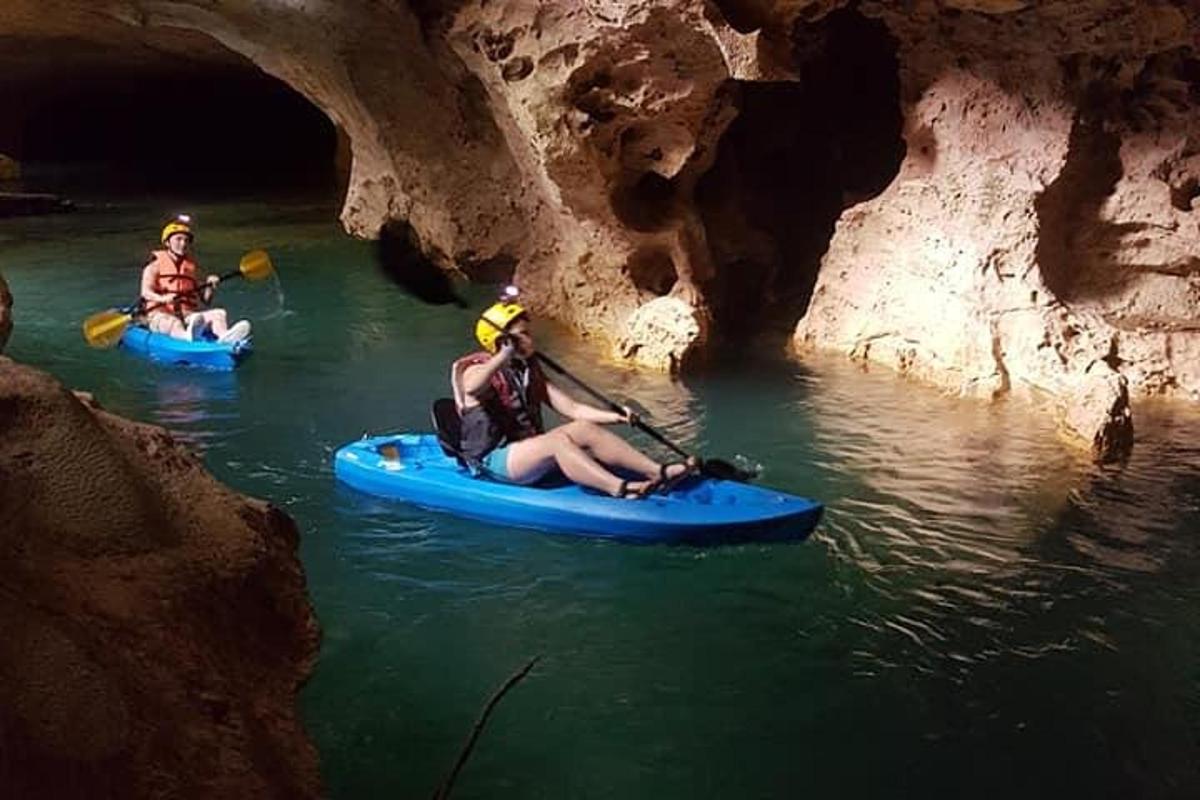 three people kayaking in a cave in the water