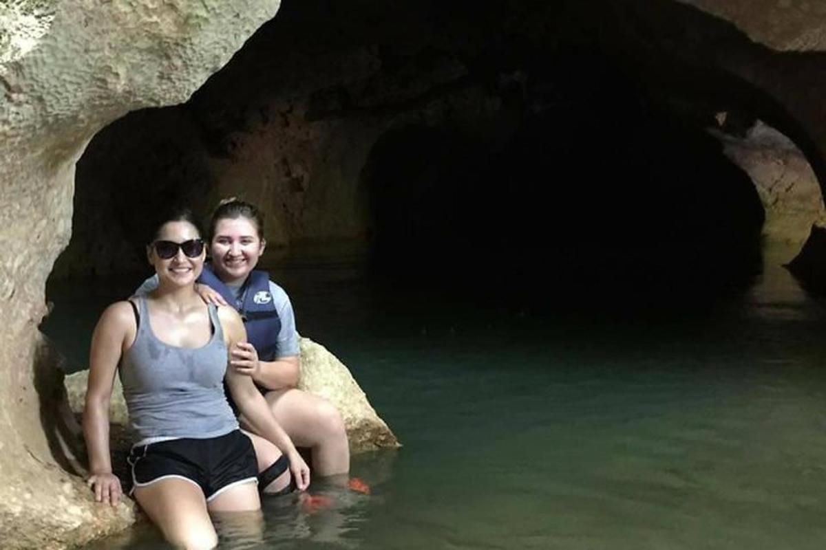 a man and woman sitting in the water in a cave