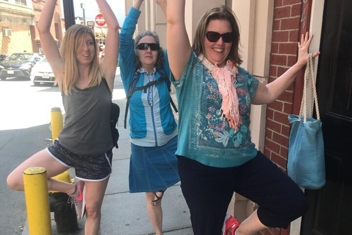 three women standing on a sidewalk with their arms in the air
