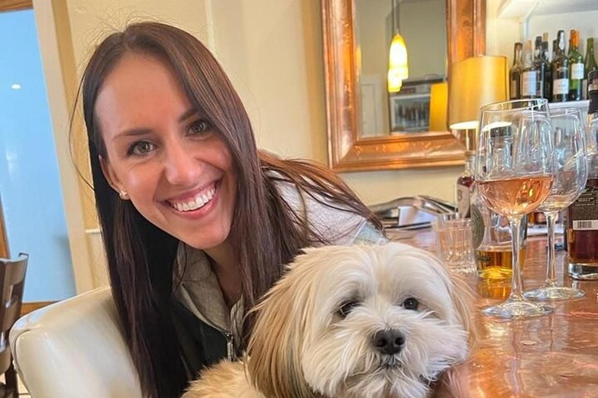 a woman sitting at a table with a white dog