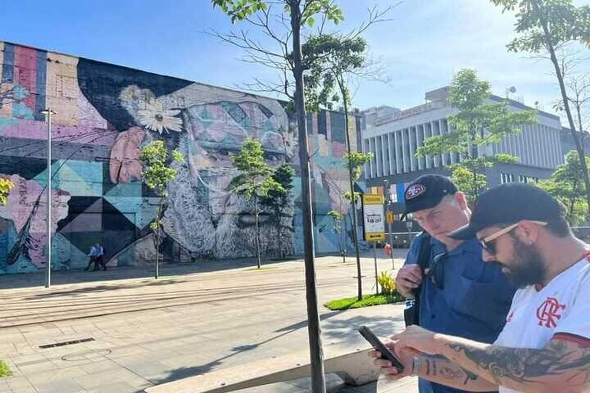 dos homes drets al costat d'un arbre mirant un telèfon mòbil