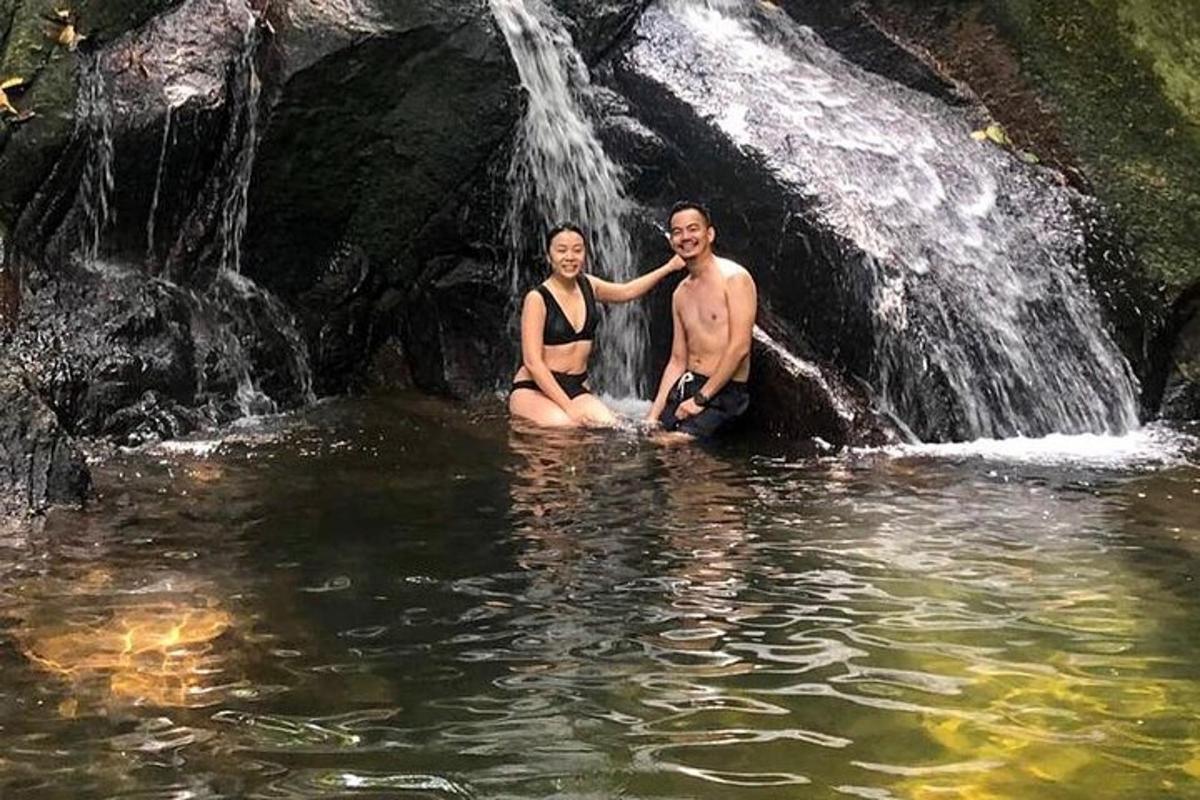 a man and woman sitting in front of a waterfall