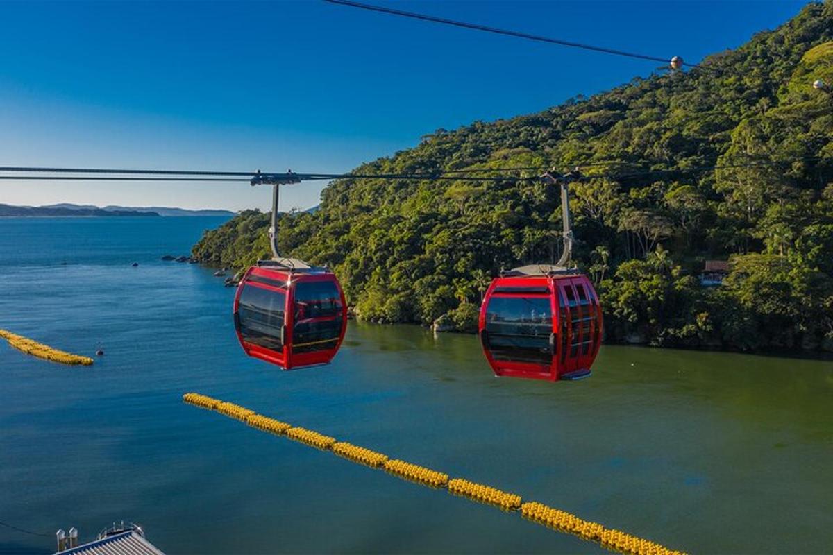 two red cable cars flying over a body of water